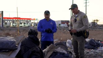 San Bernardino County Supervisor Joe Baca Jr., middle, and a sheriff's deputy speak a person experiencing homelessness during the 2025 point-in-time count in January.